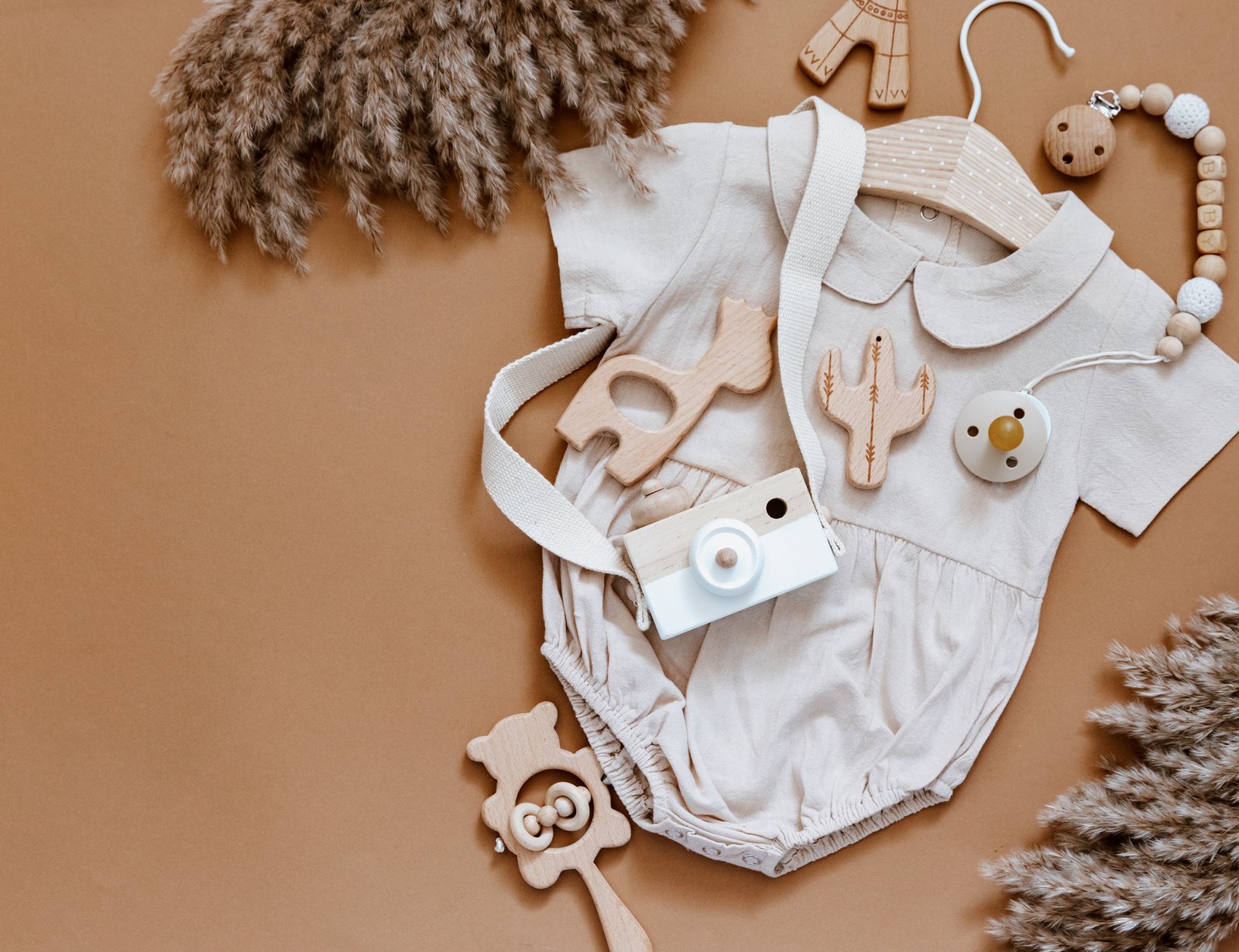 Flat lay composition with girl bodysuit, wooden camera and toys. Newborn clothes, baby staff, baby shower. Top view, flat lay
