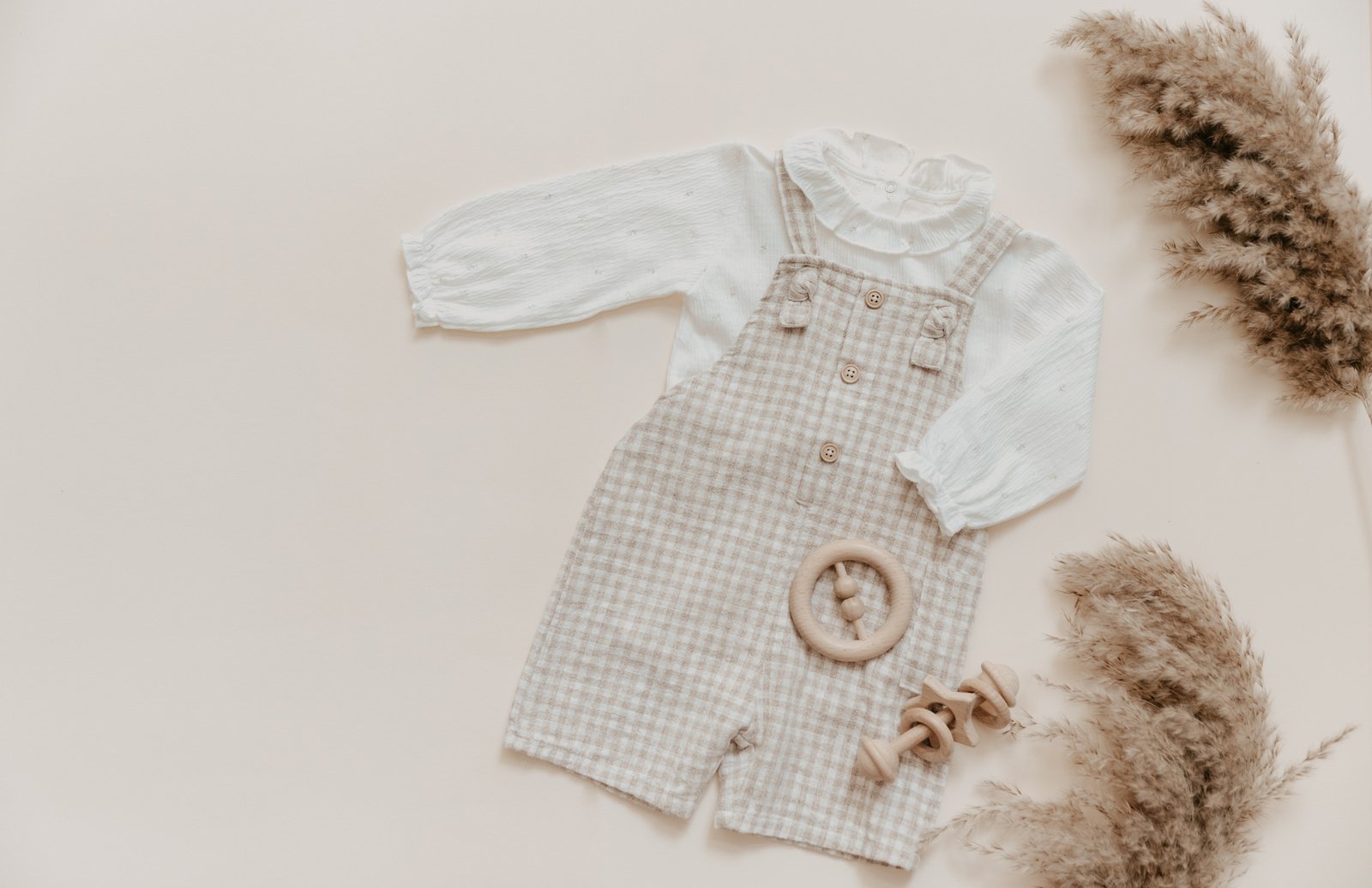 Flat lay Baby natural material accessories concept. Wooden toys, clothes and shoes on beige background. Bohemian baby fashion.
